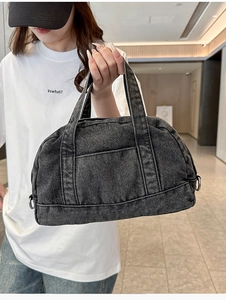 Detail of vintage washed denim handbag with dual handles and stylish seam pocket design