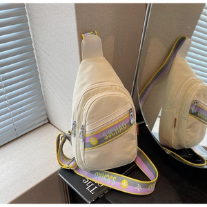 Détail du sac de poitrine en nylon crème avec bandoulière brodée colorée et zips multiples
