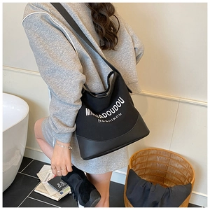 Detail of minimalist black and white canvas hobo bag with contrast leather bottom