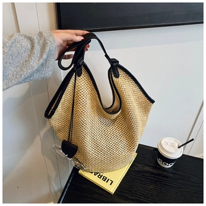 Détail du grand sac cabas en paille tressée avec anses en cuir noir et texture fine