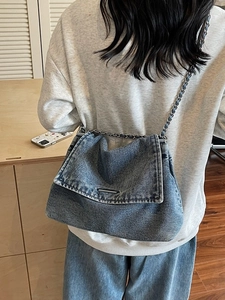 Blue washed denim shoulder bag with silver chain strap shown in a casual lifestyle setting