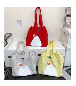 Detailed view of canvas tote bags with duck prints in red, grey, and yellow colors