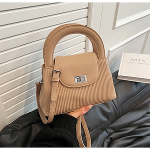 Detail of light brown tote with vertical quilting, silver twist lock and leather handle