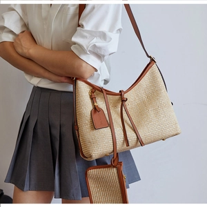 Détail du sac cabas en paille tressée avec bordure en cuir brun et petit porte-monnaie