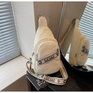 Vue détaillée du sac de poitrine en toile beige avec logo floral brodé et sangle ajustable