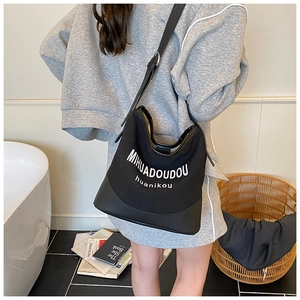 Detail of black canvas tote bag with PU leather base and adjustable shoulder strap