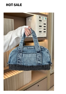 Detailed close-up of a blue and black denim pillow bag featuring silver metal D-rings