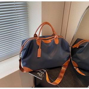 Detail of blue nylon travel bag with brown leather trim and adjustable shoulder strap