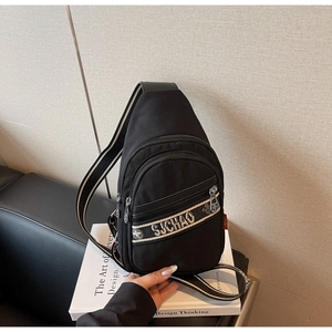 Détail du sac à bandoulière en nylon noir avec sangle rayée et sangle à lettres