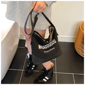 Detail of black canvas bucket bag with white logo print and wide shoulder strap