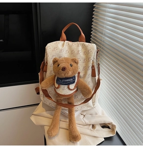 Detail of cream backpack with cartoon bear prints and a 3D plush bear ornament