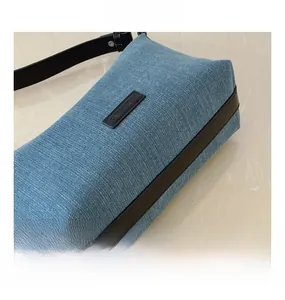 Dettaglio della borsa in denim blu che mostra il logo del marchio e i bordi in pelle nera