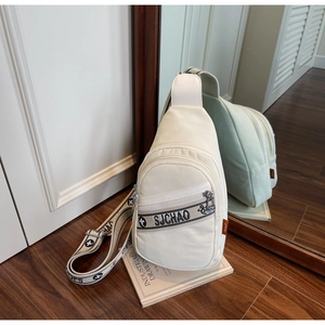 Détail du sac bandoulière crème avec sangle en jacquard et compartiments à double zip