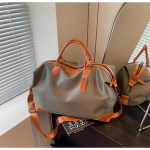 Detail view of large olive green nylon travel bag with orange leather trim and handle