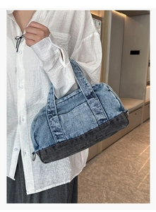 Detail of blue denim bowling bag with contrast stitching and sturdy top handles for women