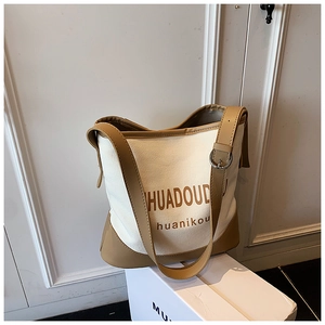 Detail of canvas bucket bag showing metal buckle and caramel leather trim