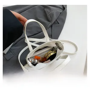 Capacità interna della borsa a secchiello in pelle bianca con cosmetici e cellulare
