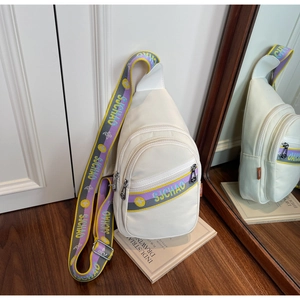 Détail du sac bandoulière blanc avec une sangle tissée violette et jaune vibrante