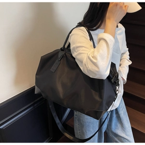 Detail view of a large black nylon travel bag with dual handles and long shoulder strap