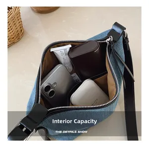 Dettaglio della capienza interna della borsa a tracolla in denim blu con oggetti