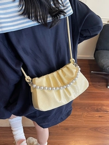 Elegante borsa a nuvola beige plissettata con manico di perle e tracolla in posa chic