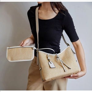 Détail d'un cabas en paille tissé à la main avec garniture en cuir blanc et pochette zippée