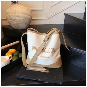 Detail view of canvas bucket bag with leather trim placed on a book in a lifestyle setting