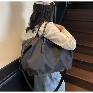 Detailed view of a large black travel tote with leather corners and adjustable strap