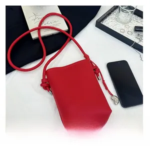 Détail d'un mini sac à bandoulière en cuir grainé rouge avec pendentif coeur argenté
