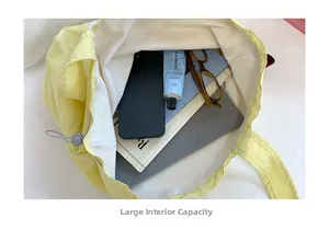 Top view of the large capacity interior of a yellow canvas tote bag showing daily items