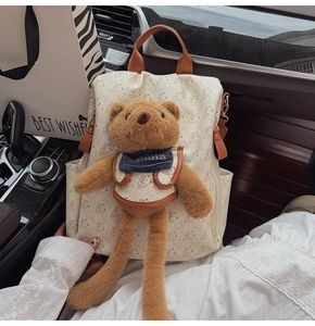 Detail of white PU backpack with printed bears and a plush bear pendant inside a car