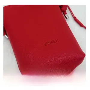 Détail d'un sac bandoulière en cuir rouge grainé avec logo SUNWOMEN et cordons argentés