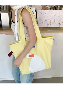 Detail of yellow canvas tote bag with duck print featuring drawstring closure for students