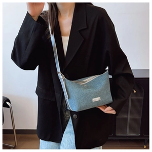 Dettaglio borsa a mezzaluna in denim azzurro con zip argento e logo in metallo