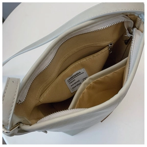 Interior view of the cream shoulder bag showing the brown lining and zipper pocket