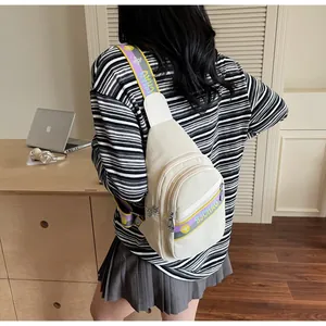 Vue détaillée du sac bandoulière avec sangle logo violette et jaune sur un bureau