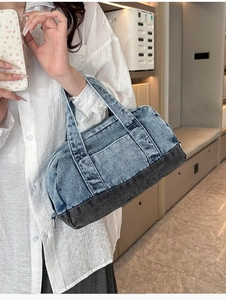 Detail view of denim tote bag showing cylindrical shape and blue patchwork texture