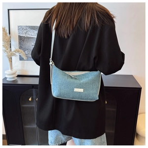 Dettaglio borsa in denim blu con logo Carpediem metallico su blazer nero chic