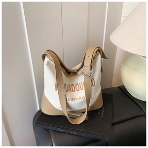 Detailed view of canvas and leather bucket bag featuring elegant typography and metal buckle
