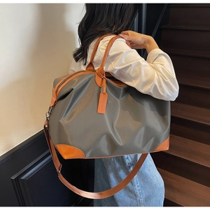 Close-up of waterproof grey nylon travel bag with orange leather trim and brand tag