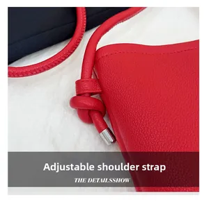 Détail du sac bandoulière en cuir rouge avec nœud sur la sangle réglable