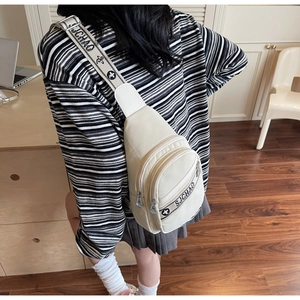Détail du sac bandoulière en toile crème avec poches multiples et sangle imprimée