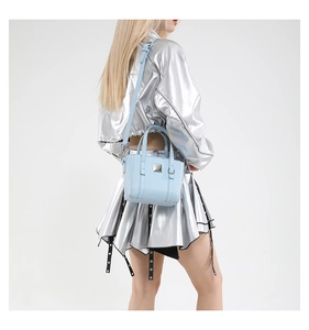 Dettaglio della mini borsa tote azzurra con trama litchi e rivetti argentati sul modello