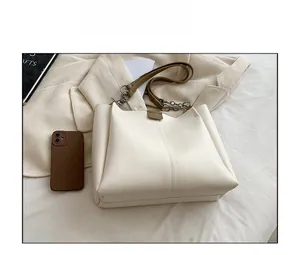 Close-up of minimalist cream tote bag with brown strap and silver chain detail