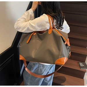 Detailed shot of an olive nylon travel bag with brown leather accents on a model