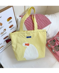 Detail of cute yellow canvas tote bag with Dazui duck cartoon and blue brand label