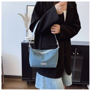 Dettaglio della borsa in denim azzurro con finiture argento e logo metallico distintivo