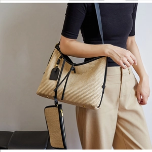 Détail du cabas tissé beige avec garniture en cuir noir et pochette zippée assortie