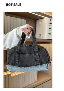 Detail view of denim tote bag with color-block stitching and metal zipper