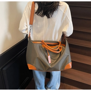 Deep green travel bag with brown leather details shown on model in stair setting
